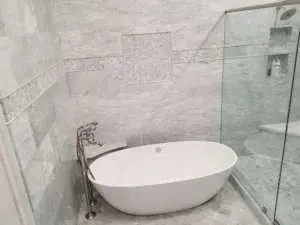 Elegant freestanding tub with marble tile surround and glass shower partition