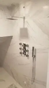 Custom shower design featuring multiple shower fixtures, body sprays, and premium tile work